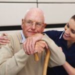 'caretaker with an older man using a cane'