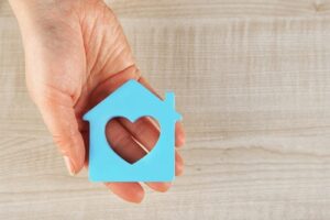 hand holding a cutout shaped like a house with a heart in it
