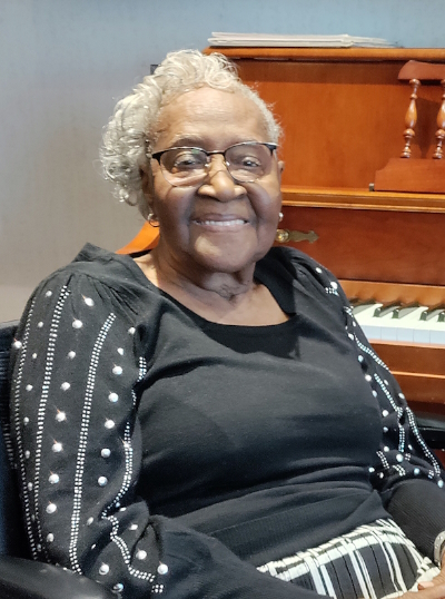 Mary Robinson smiling in front of a piano