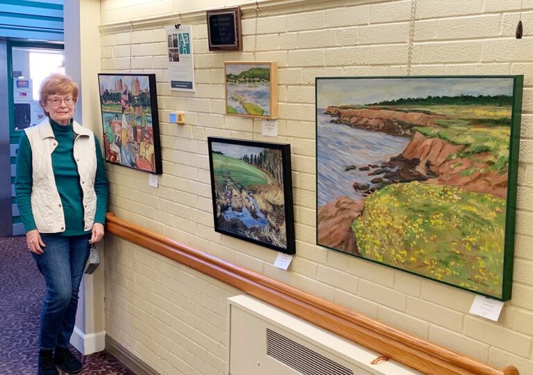 artist marilyn ladieu standing next to some of her featured works