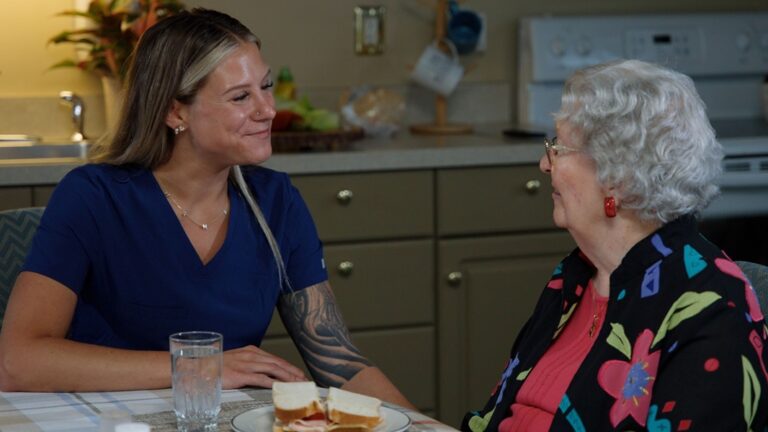 nurse and personal care resident smiling in a kitchen