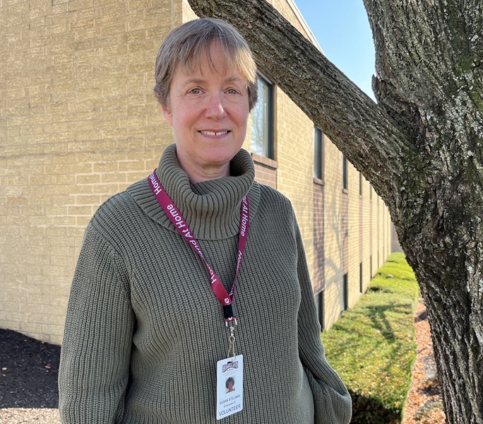 Volunteer Susan Stillman smiling outside by a tree