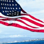 banner of an american flag flying over a shore