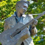 banner featuring a statue of elvis in front of trees