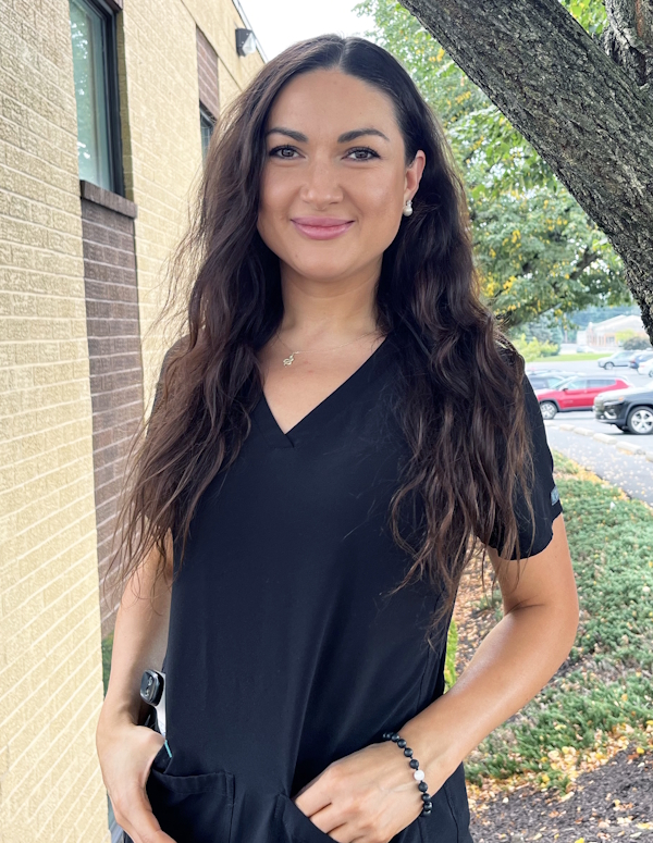 Nurse Elizabeth Terekh in scrubs next to a tree