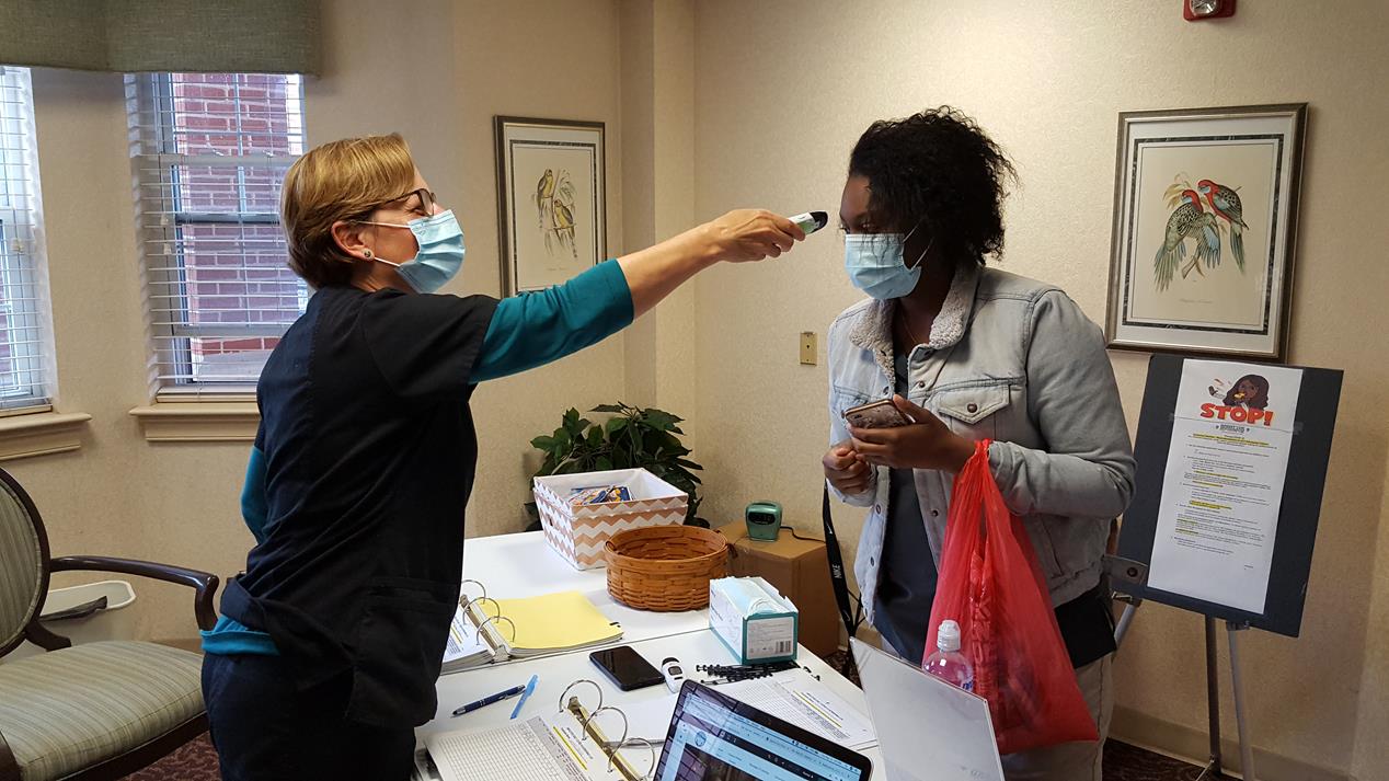Lin Roussel (L) conducting a portion of the twice daily employee screening at Homeland Center