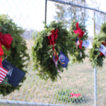'wreaths dedicated to veterans hanging on a chain link fence'
