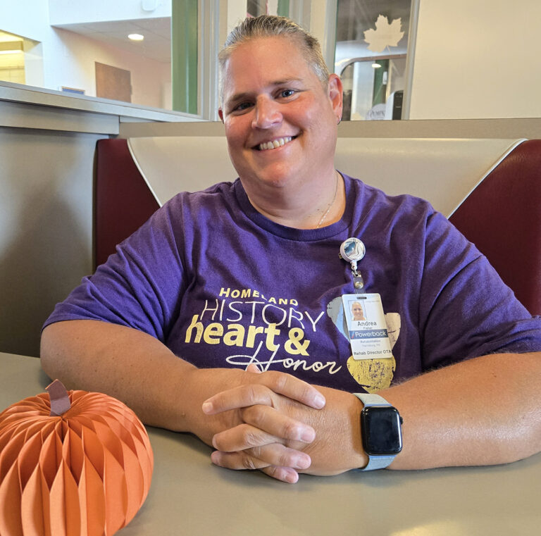 Andrea Fisher smiling next to a decorative pumpkin