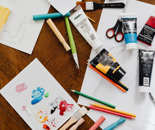 'a table with various art supplies like paint and colored pencils'