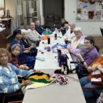 'a group of happy people knitting, sewing, and crocheting together for a good cause'